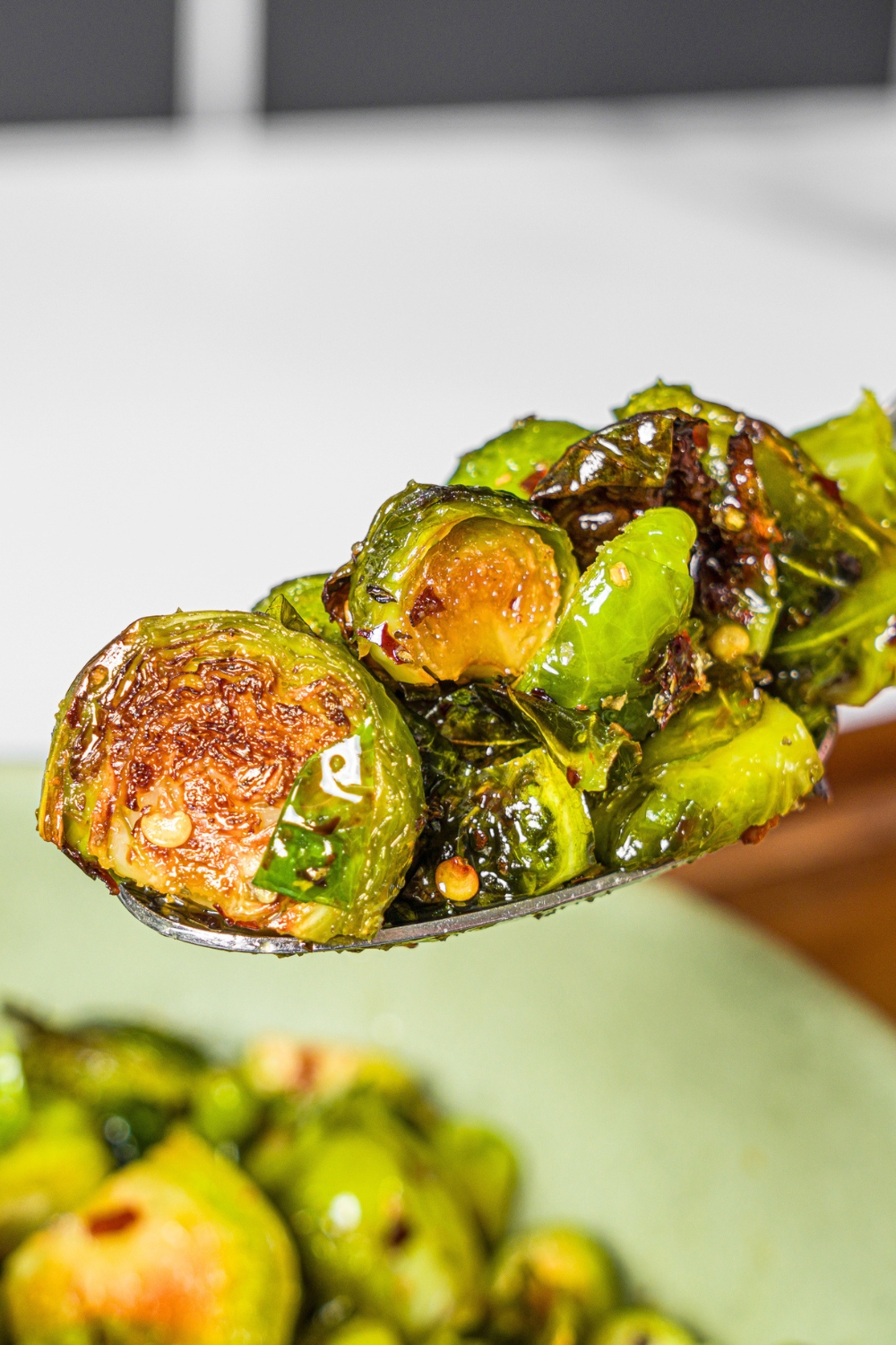 A spoon with crispy brussel sprouts on it.