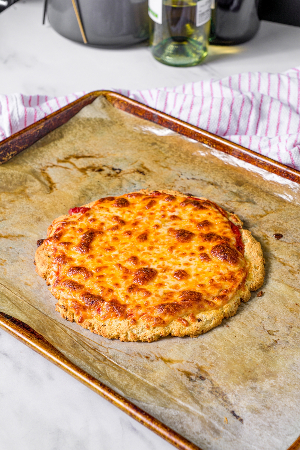 A baked high protein pizza on a sheet of parchment paper on a baking tray.
