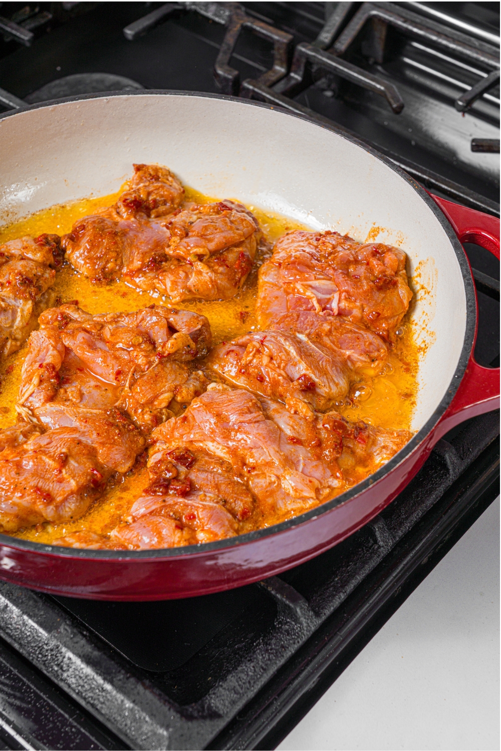 A skillet with seasoned chicken thighs.