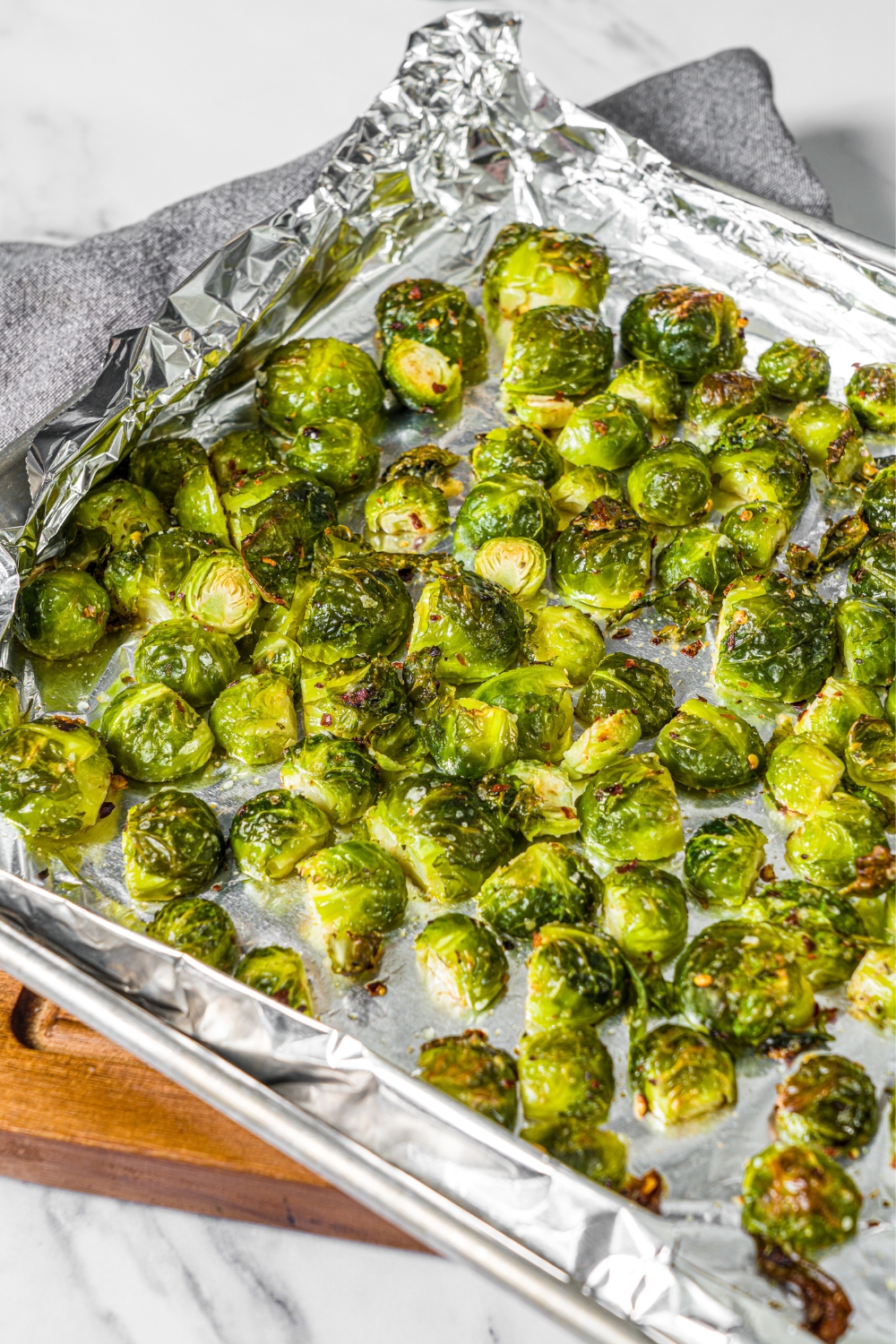 A bunch of crispy brussels sprouts spread out on a foil lined baking tray.