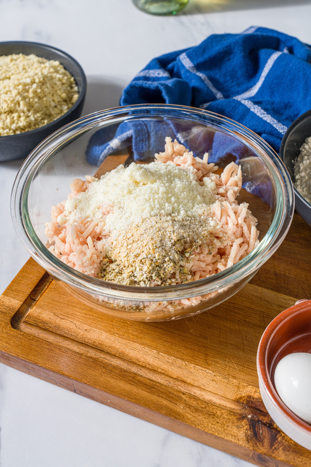 Panko, breadcrumbs, and seasonings with ground chicken in a glass bowl.