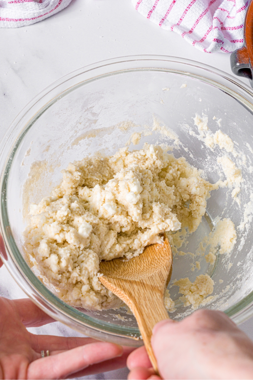 A wooden spoon in a glass bowl mixing a protein pizza crust together.