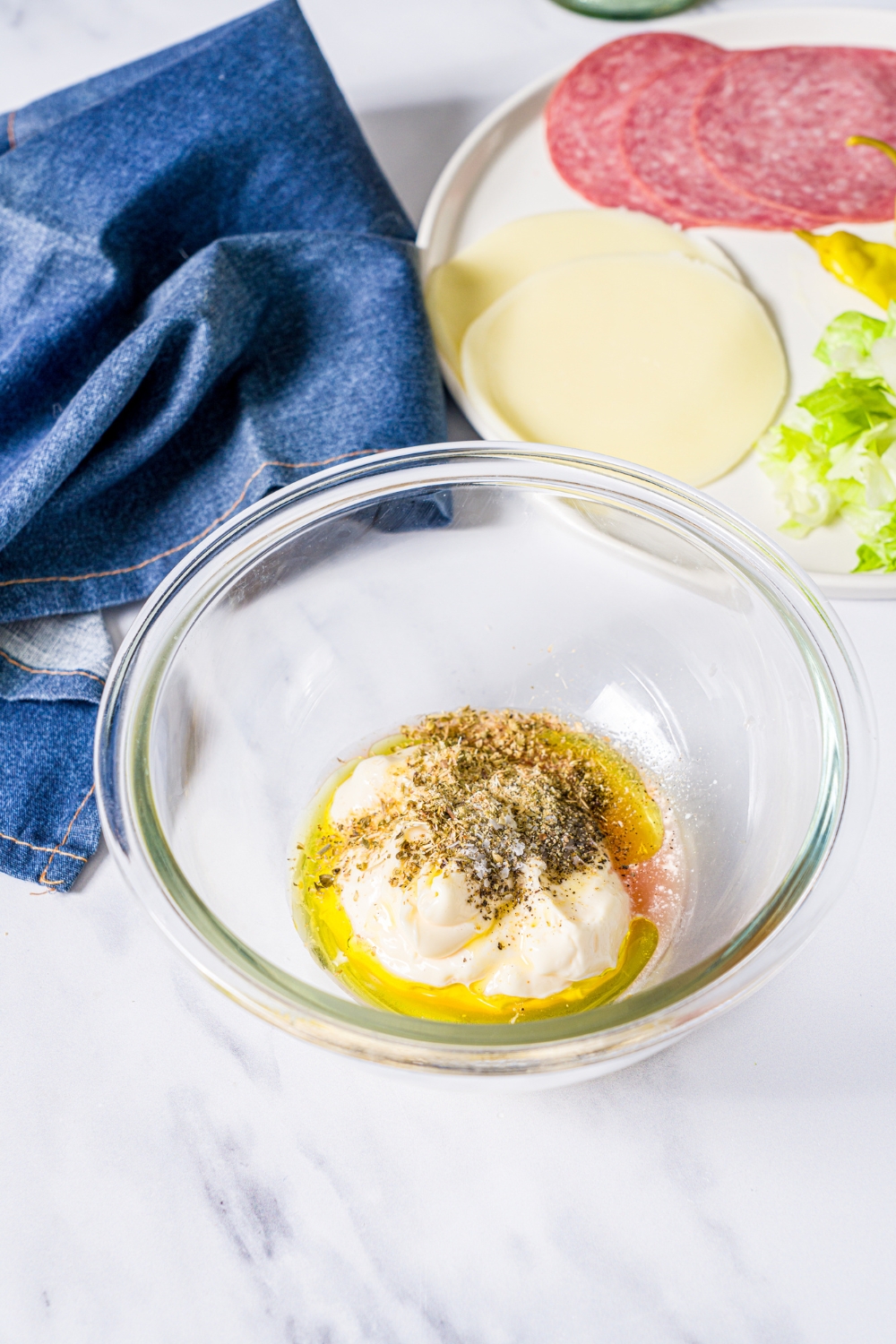 Mayo, vinegar, and Italian seasonings in a glass bowl.