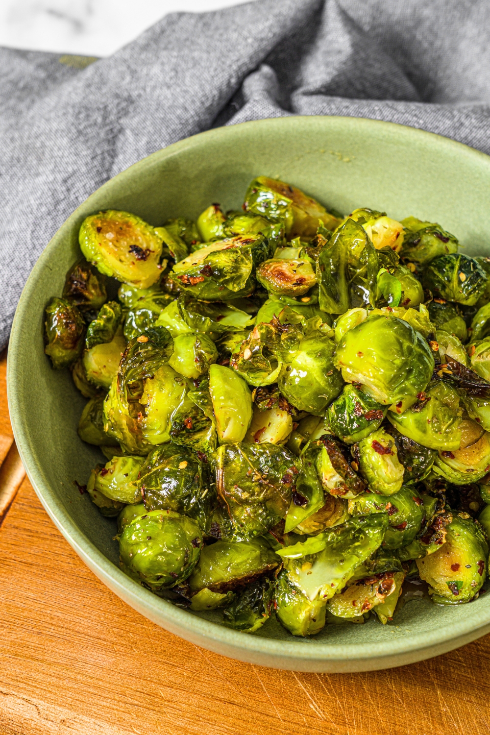 A green bowl that is filled with crispy spicy maple glazed brussel sprouts.