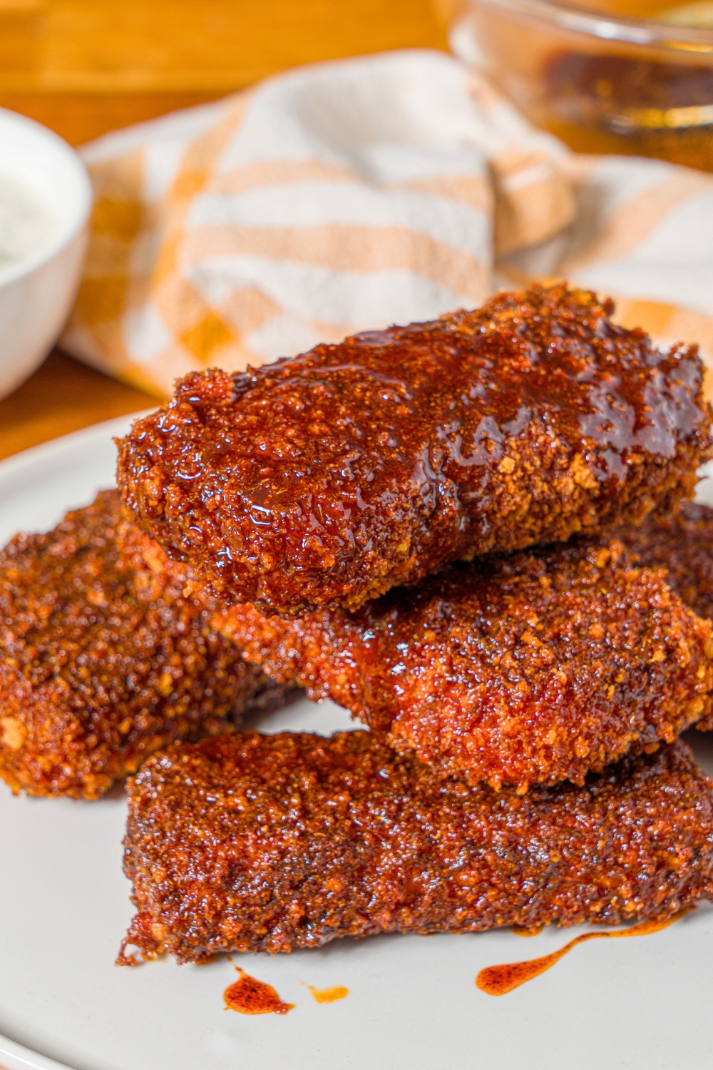 A stack of four Nashville hot mozzarella sticks on a white plate.