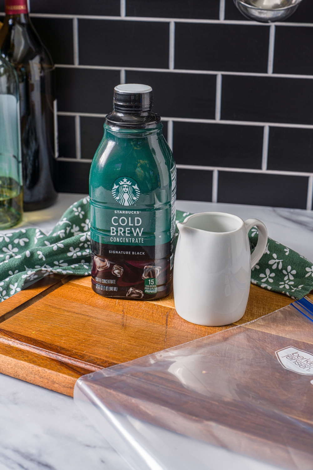 A wooden board with cold brew concentrate, a carafe of milk, and a freezer bag.