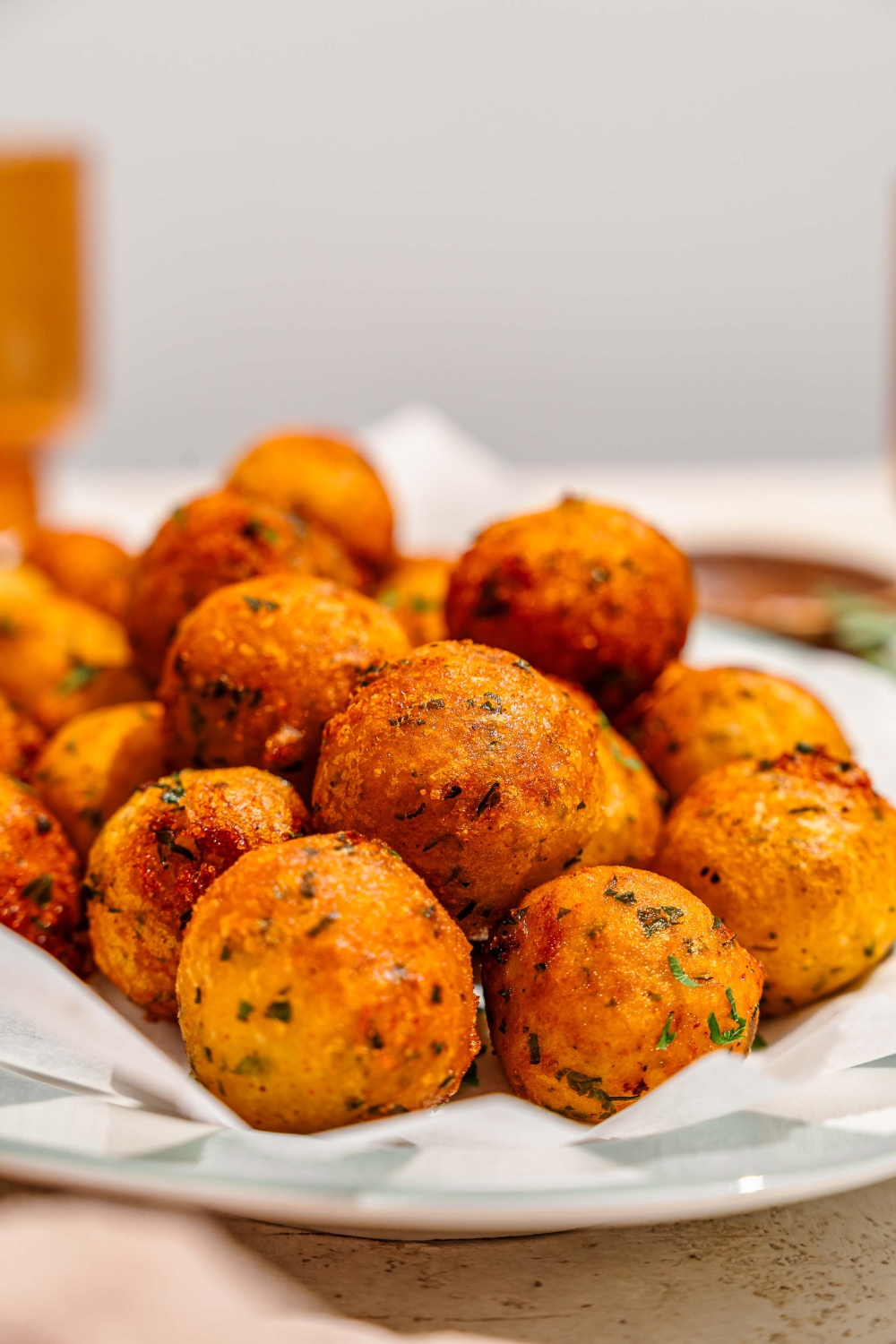 A platter lined with parchment paper with crispy potato balls garnished with fresh parsley.