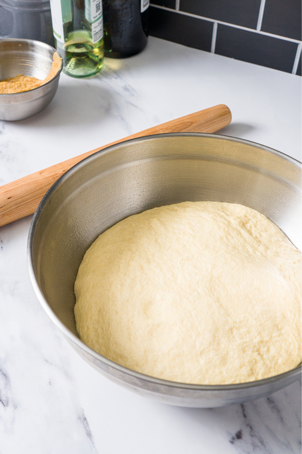 A stainless steel bowl with pufffy cinnamon roll dough in it.