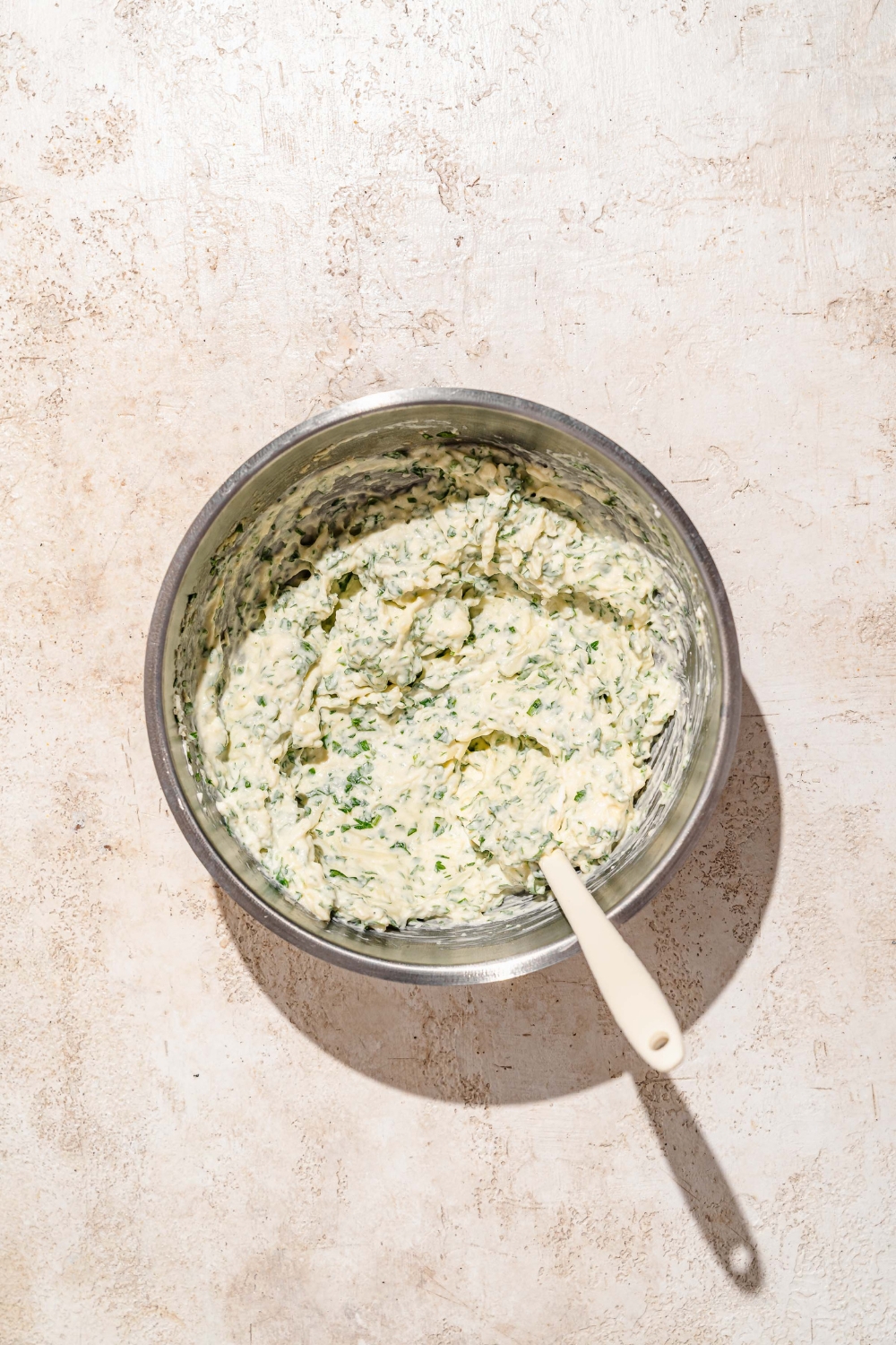 A bowl with a ricotta mixture. The bowl is on a tan counter.