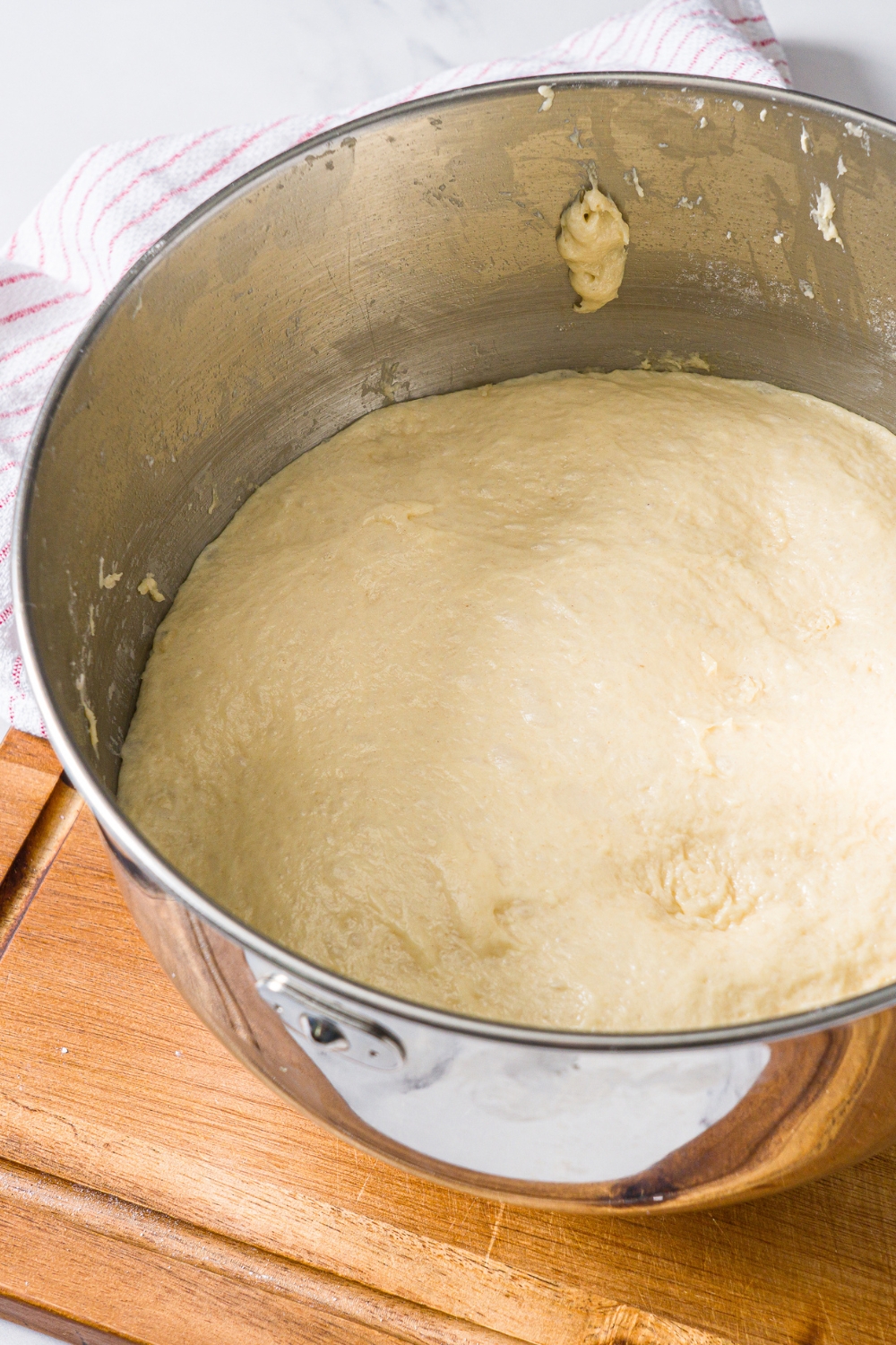 A large mixing bowl with pull apart bread dough. The bowl is on a wooden board.