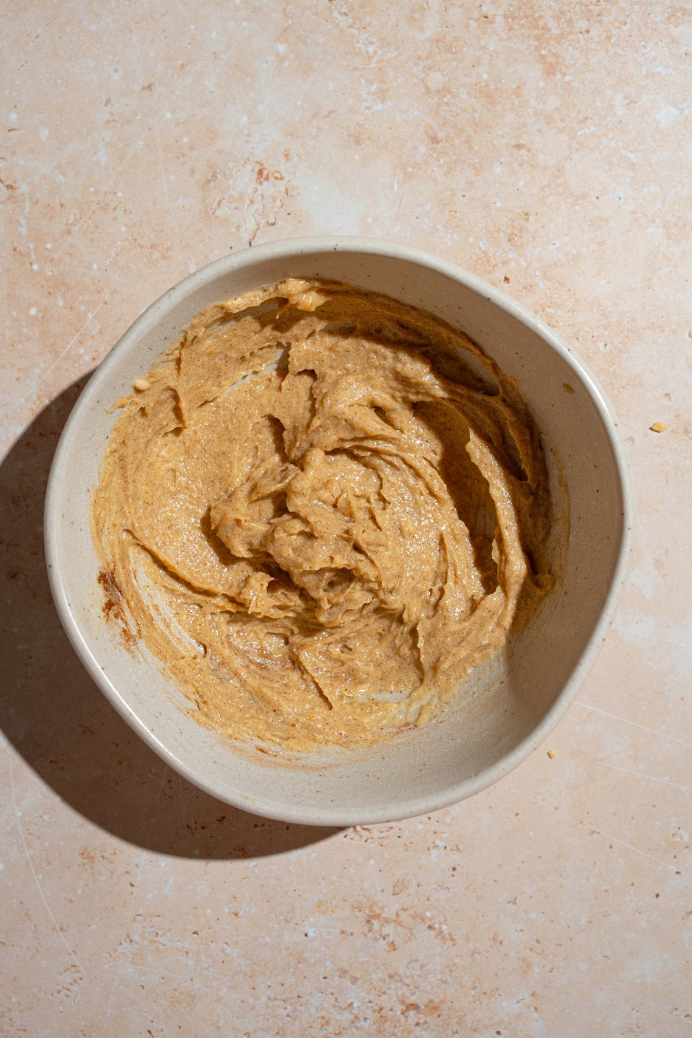 A large bowl with a cinnamon swirl mixture. The bowl is on a tan counter.