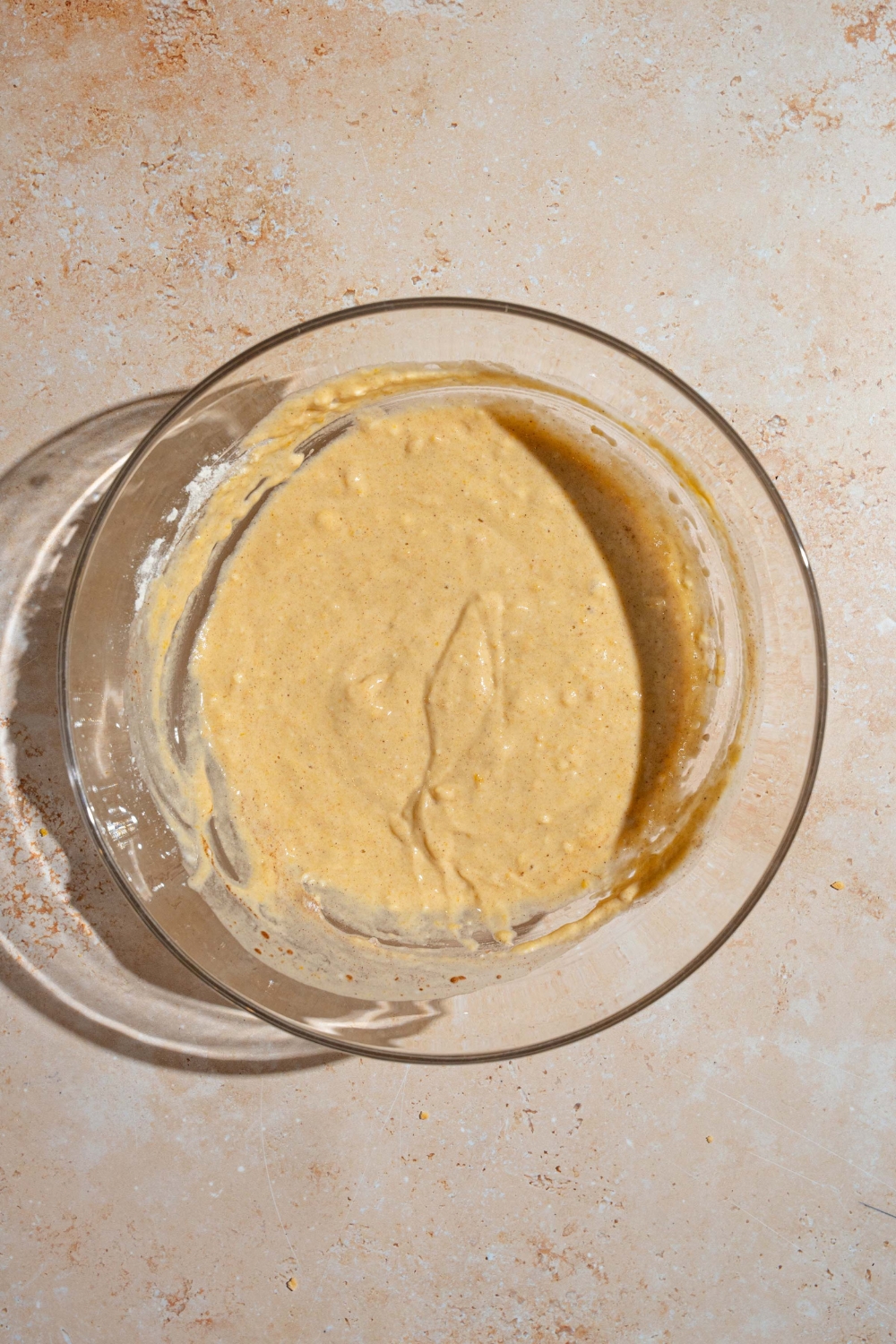 A large bowl with pumpkin pancake batter. The bowl is on a tan counter.