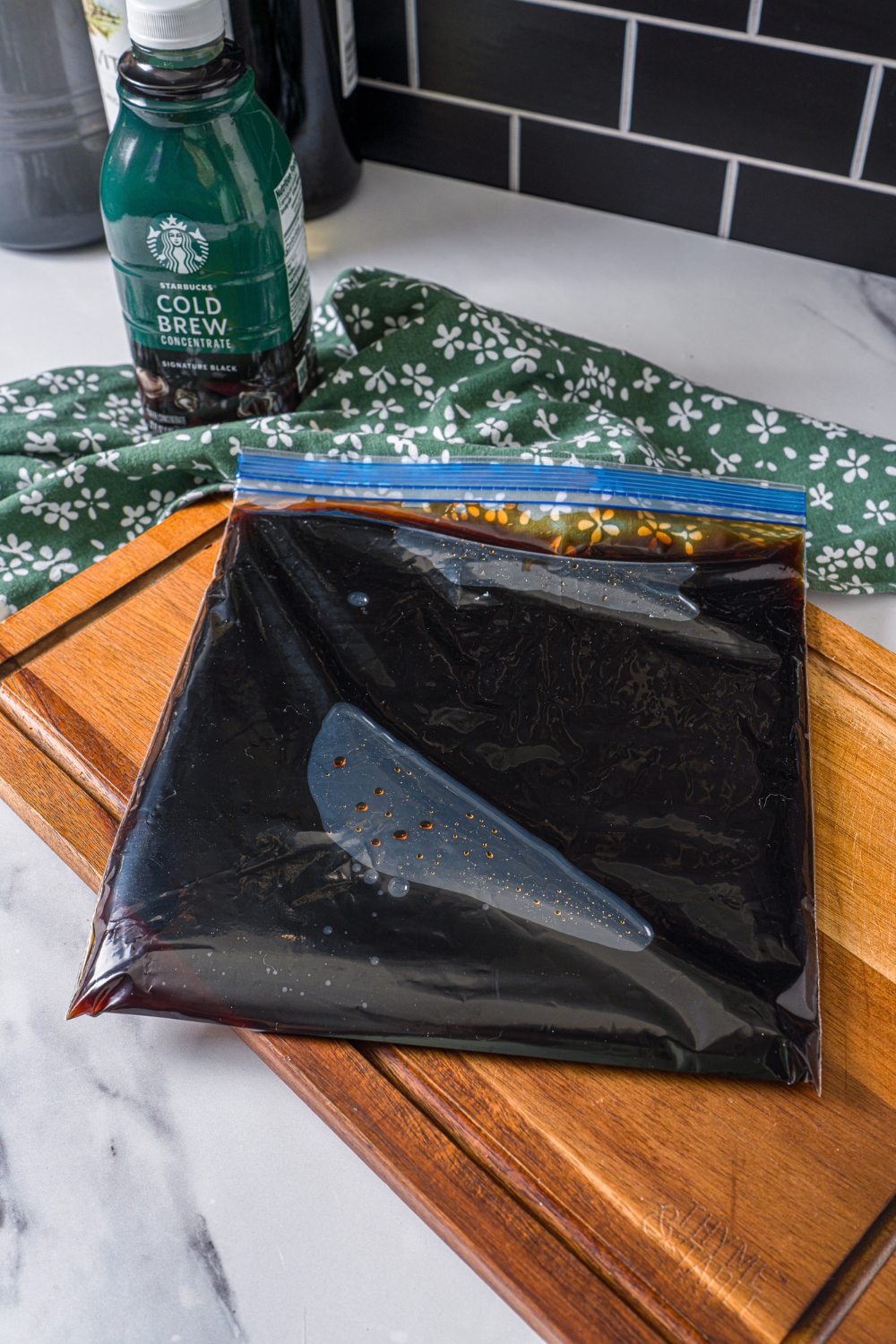 A freezer bag laying flat filled with coffee. The bag is on a wooden board.