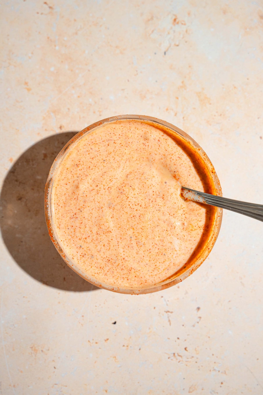 A large bowl with a hot honey sauce mixture with a spoon in the sauce. The bowl is on a tan counter.
