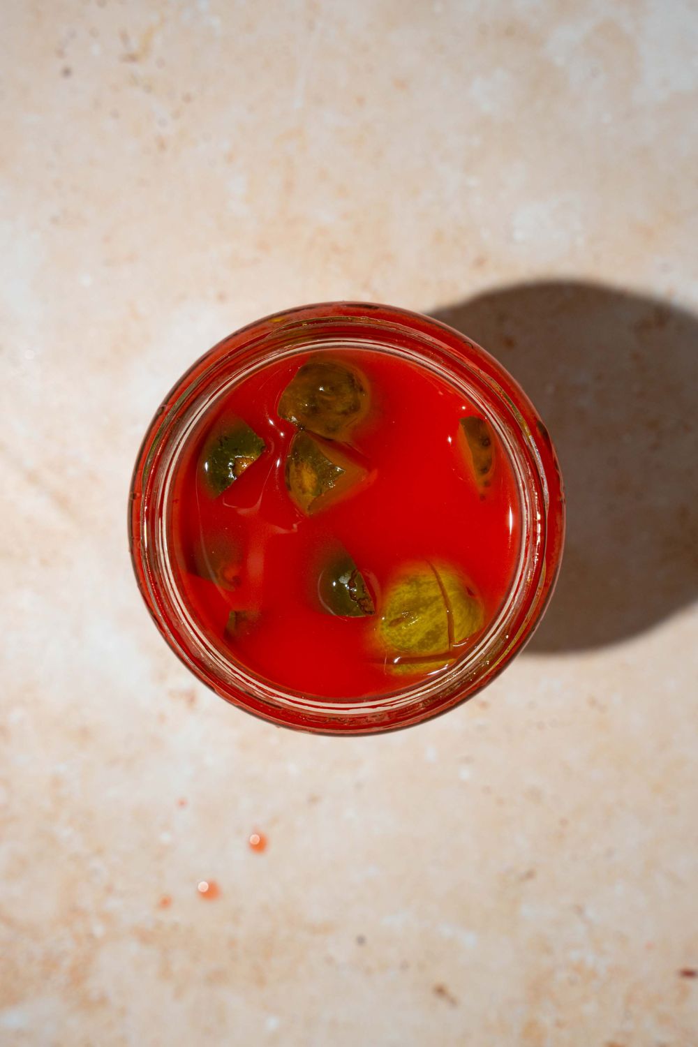 A jar of kool aid pickles. The jar is on a tan counter.