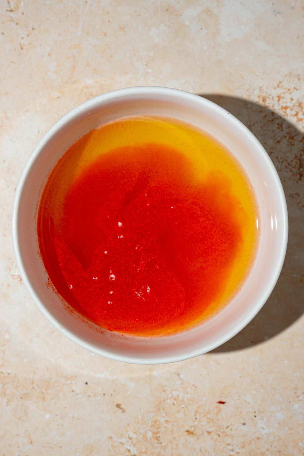 A large bowl with kool aid mixing with pickle brine and sugar. The bowl is on a tan counter.