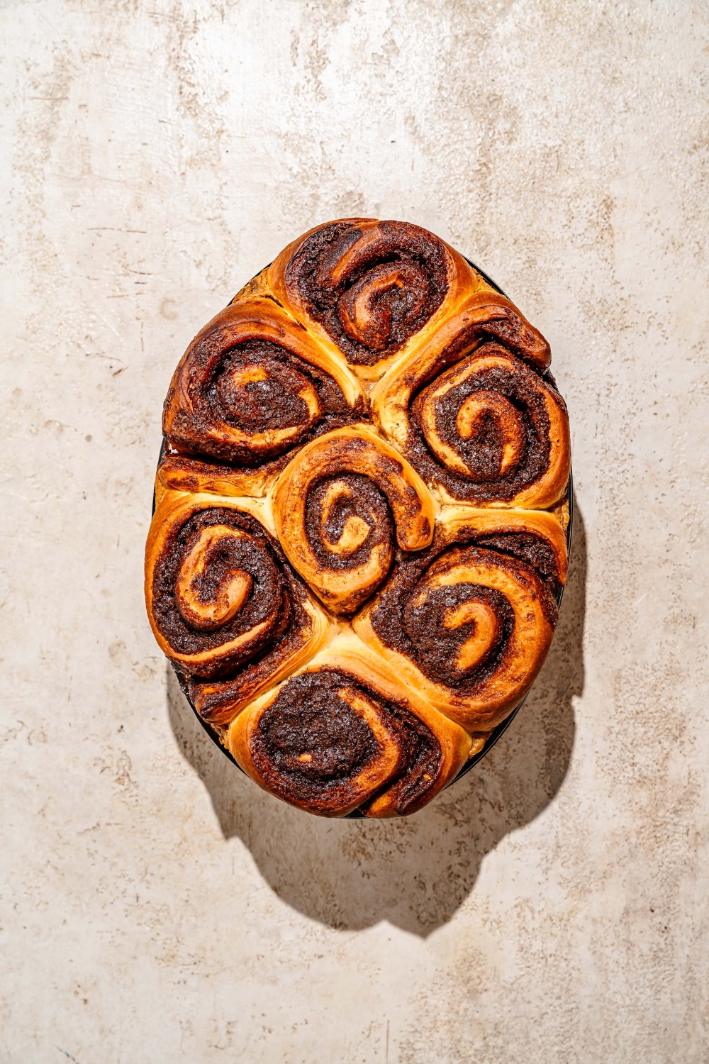 A baking dish with baked pecan caramel sticky buns. The dish is on a tan counter.
