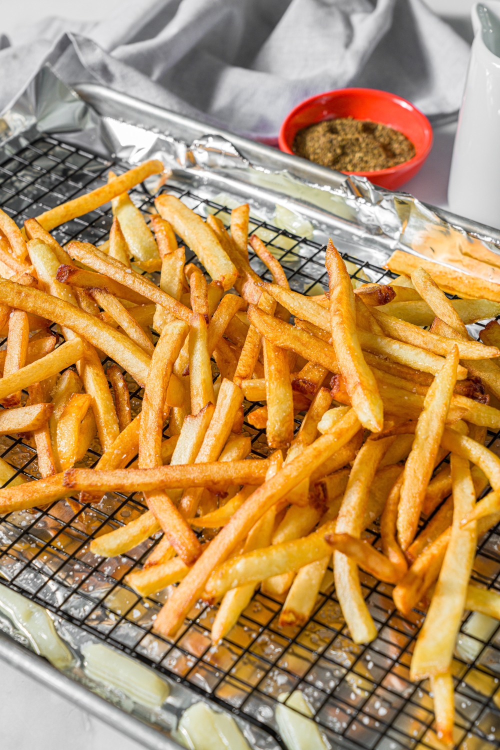 A baking sheet lined with foil with a wire rack and crispy fries on top.