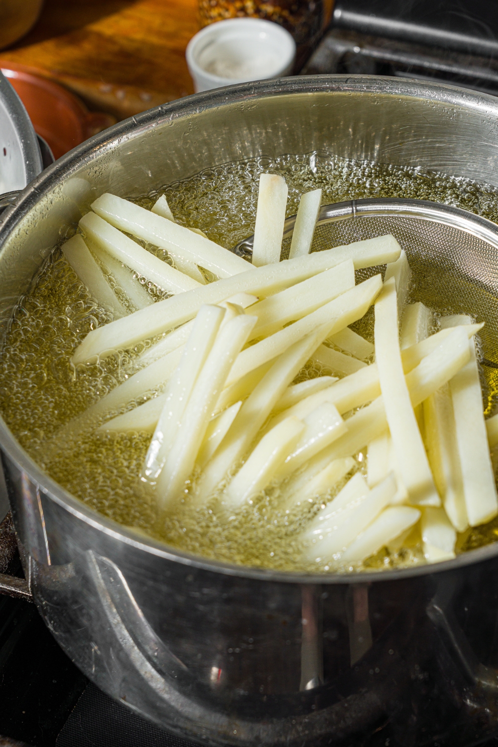 A large pot with sliced fries frying in oil.