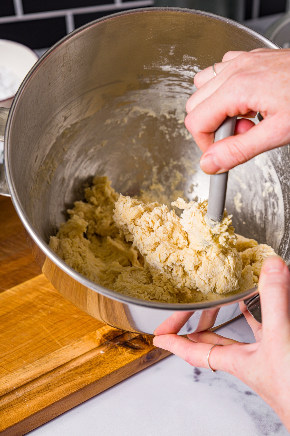 A large mixing bowl with a spatula mixing ingredients to make beignet dough.