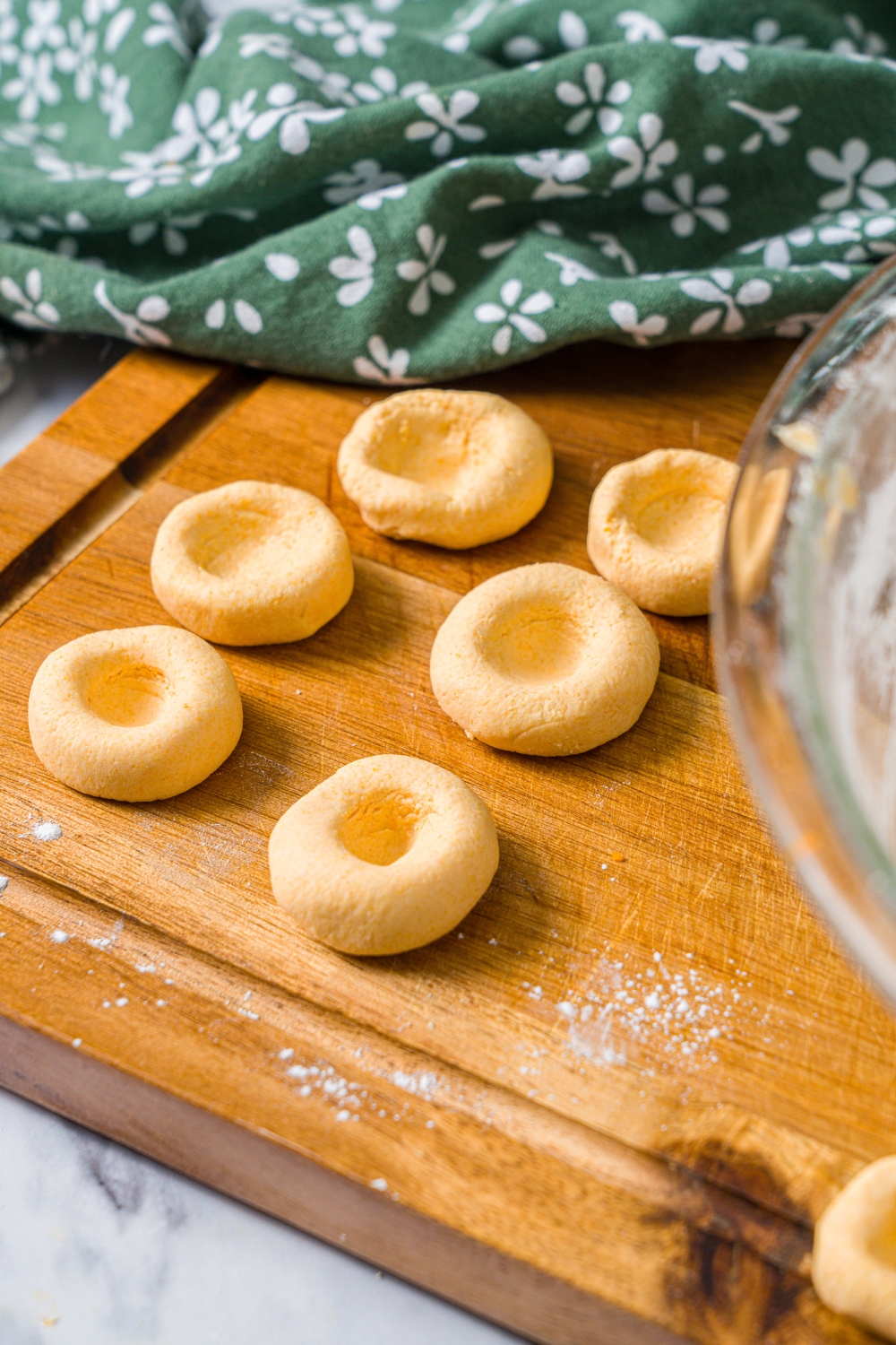 A wooden board with carrot noodle dough shaped into buttons.