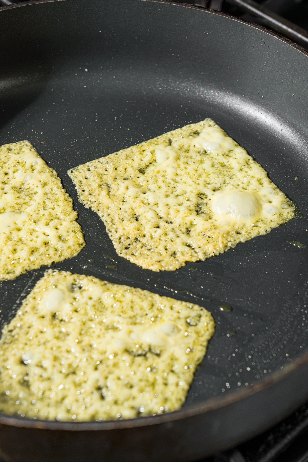 A skillet with cooked slices of gouda cheese.