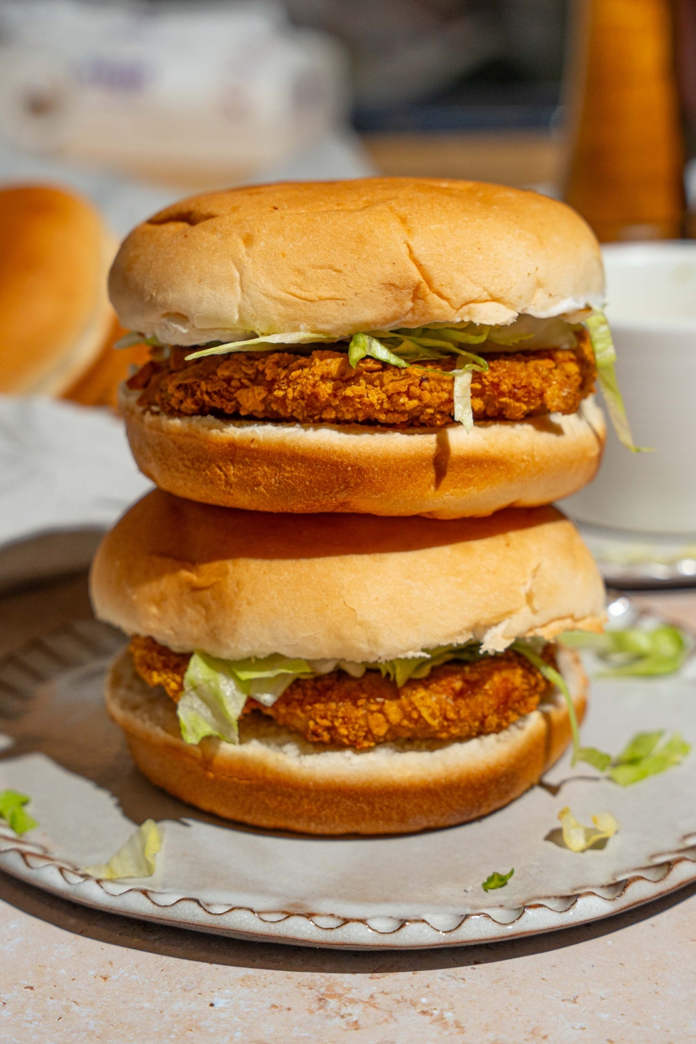 A plate with two McChicken sandwiches with one stacked on the other. The plate is on a tan counter.
