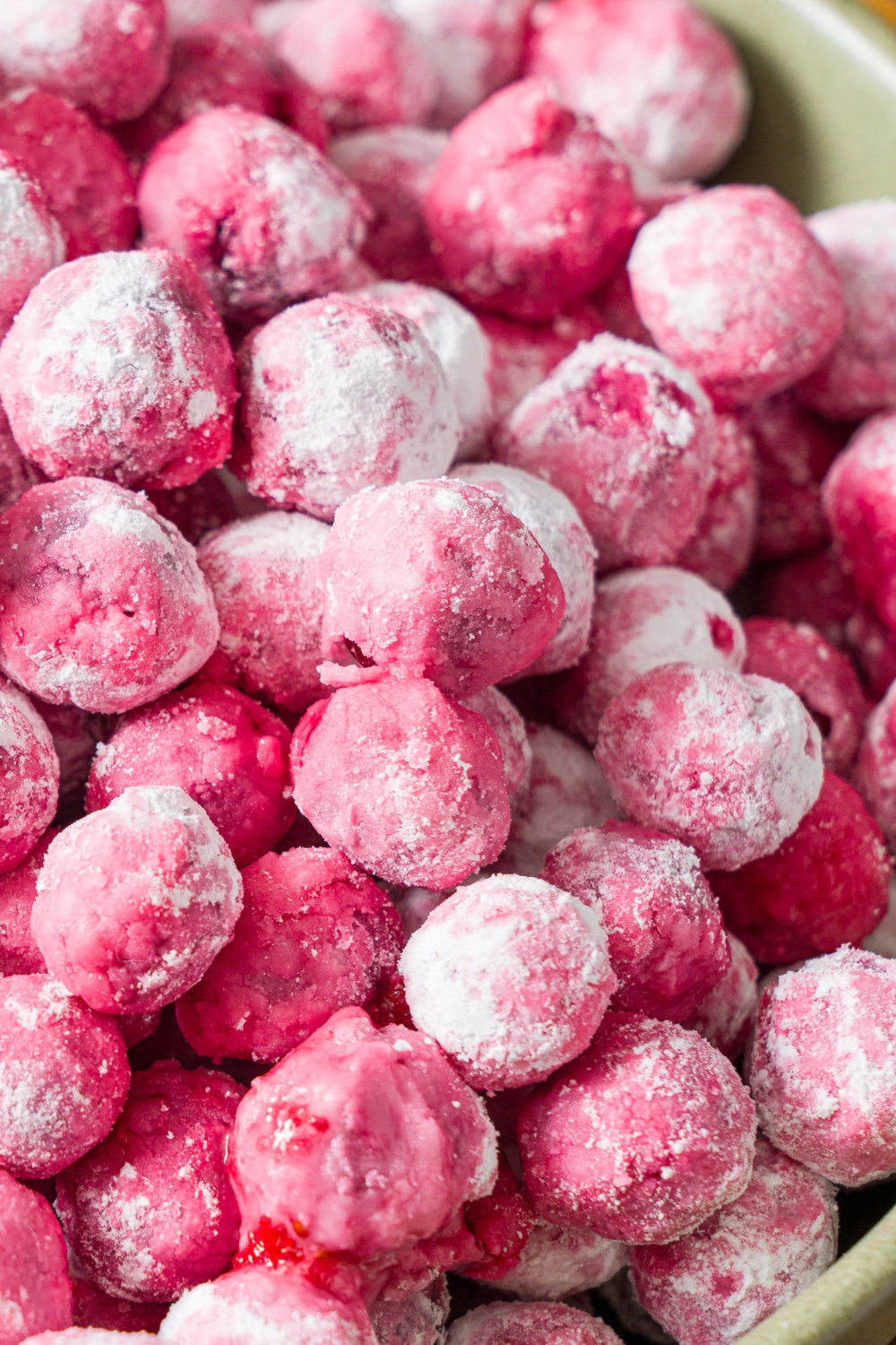 A close up of candied cranberries in a green bowl.