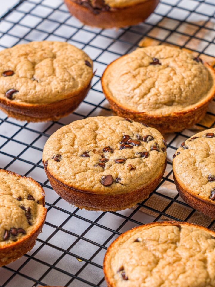 A bunch of chocolate chip banana protein muffins on a wire rack.
