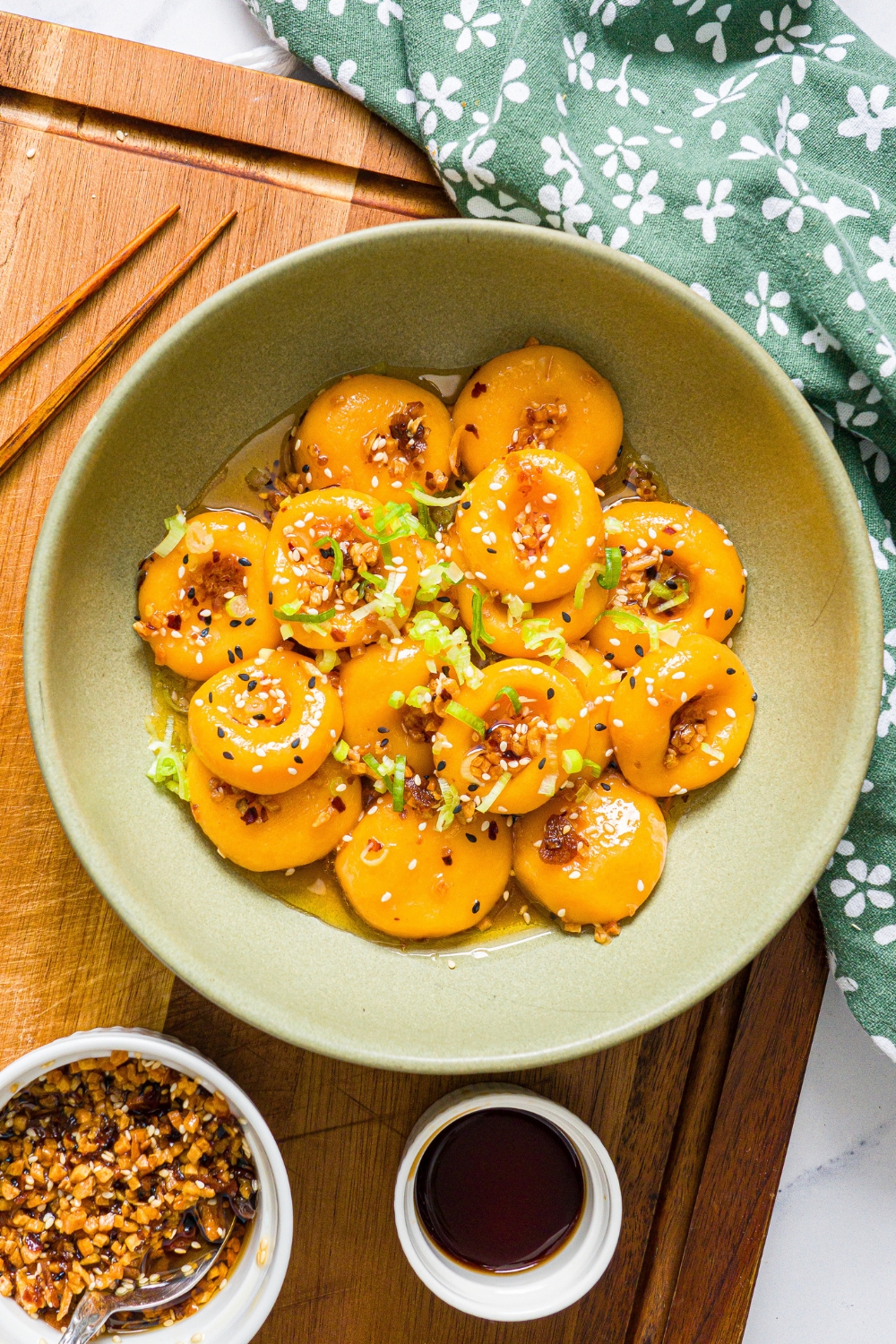 Carrot button noodles with chili crisp sauce on top in a green bowl.