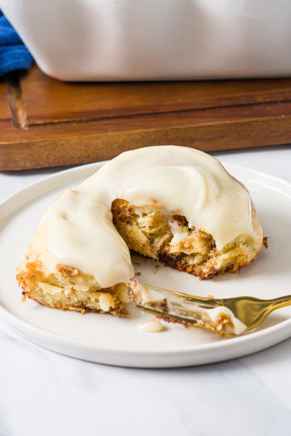 A cookie dough cinnamon roll that is cut in half with part of the cinnamon roll opened up on a white plate.