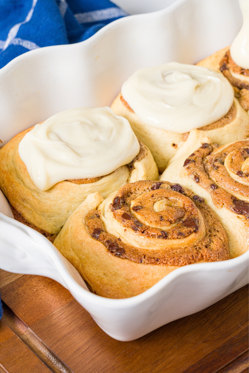 Two cookie dough, cinnamon rolls with two frosted cookie dough, cinnamon rolls behind it all in a white tray.