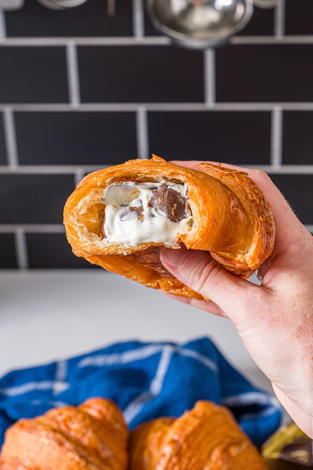 A hand holding a croissant ice cream bar.