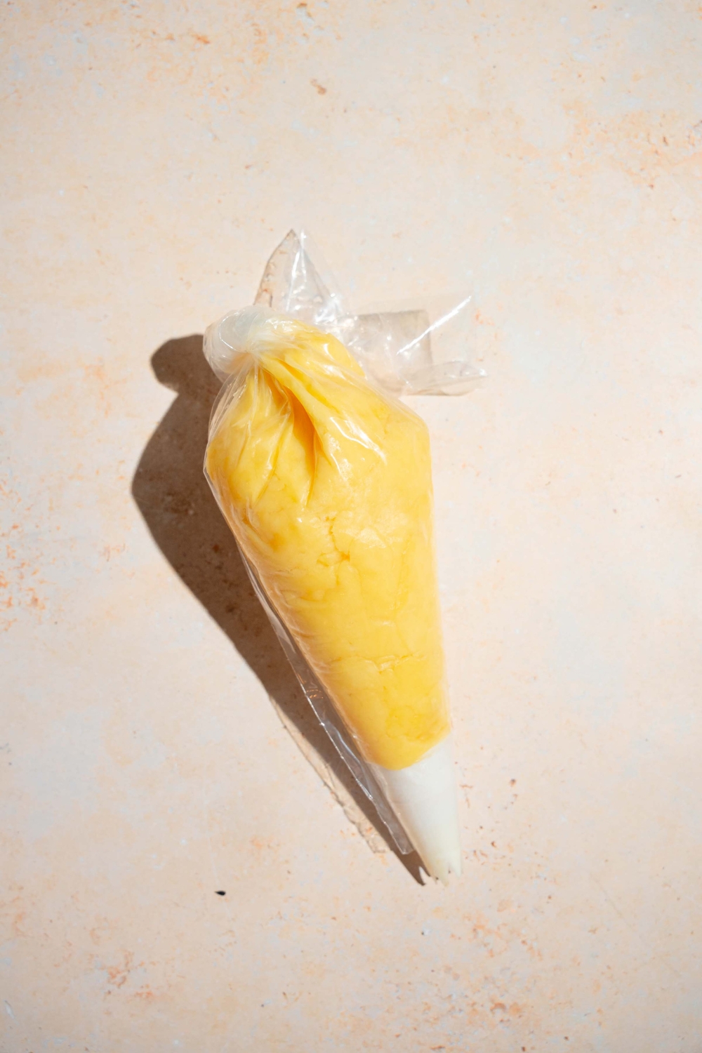 Churro dough in a piping bag on a white counter.