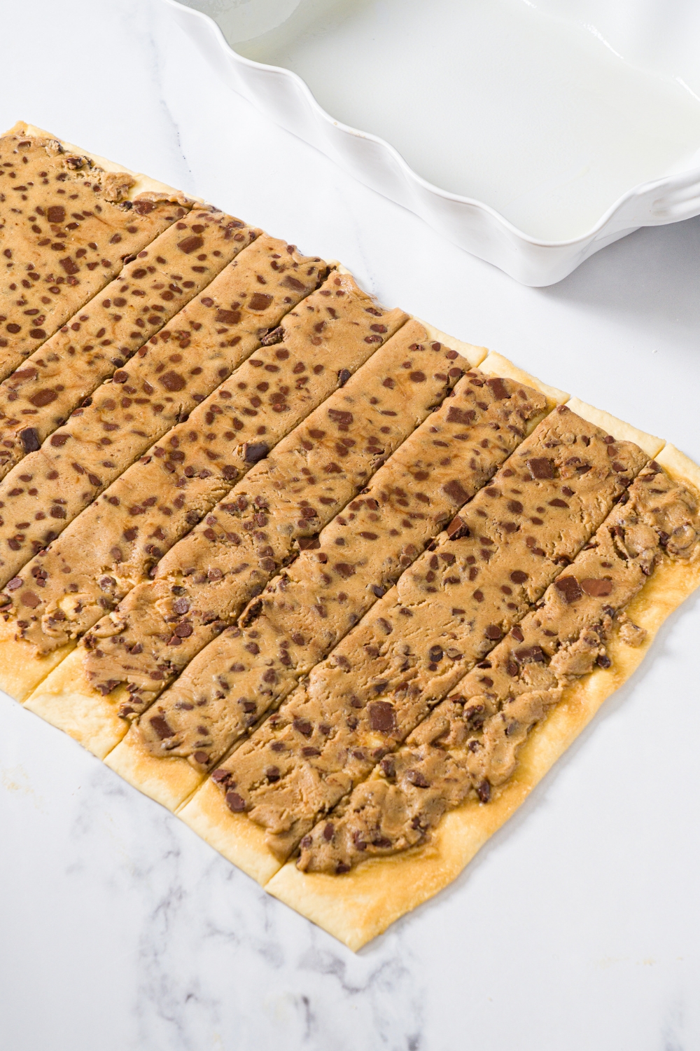 A layer of chocolate chip cookie dough flattened on top of cinnamon roll dough.