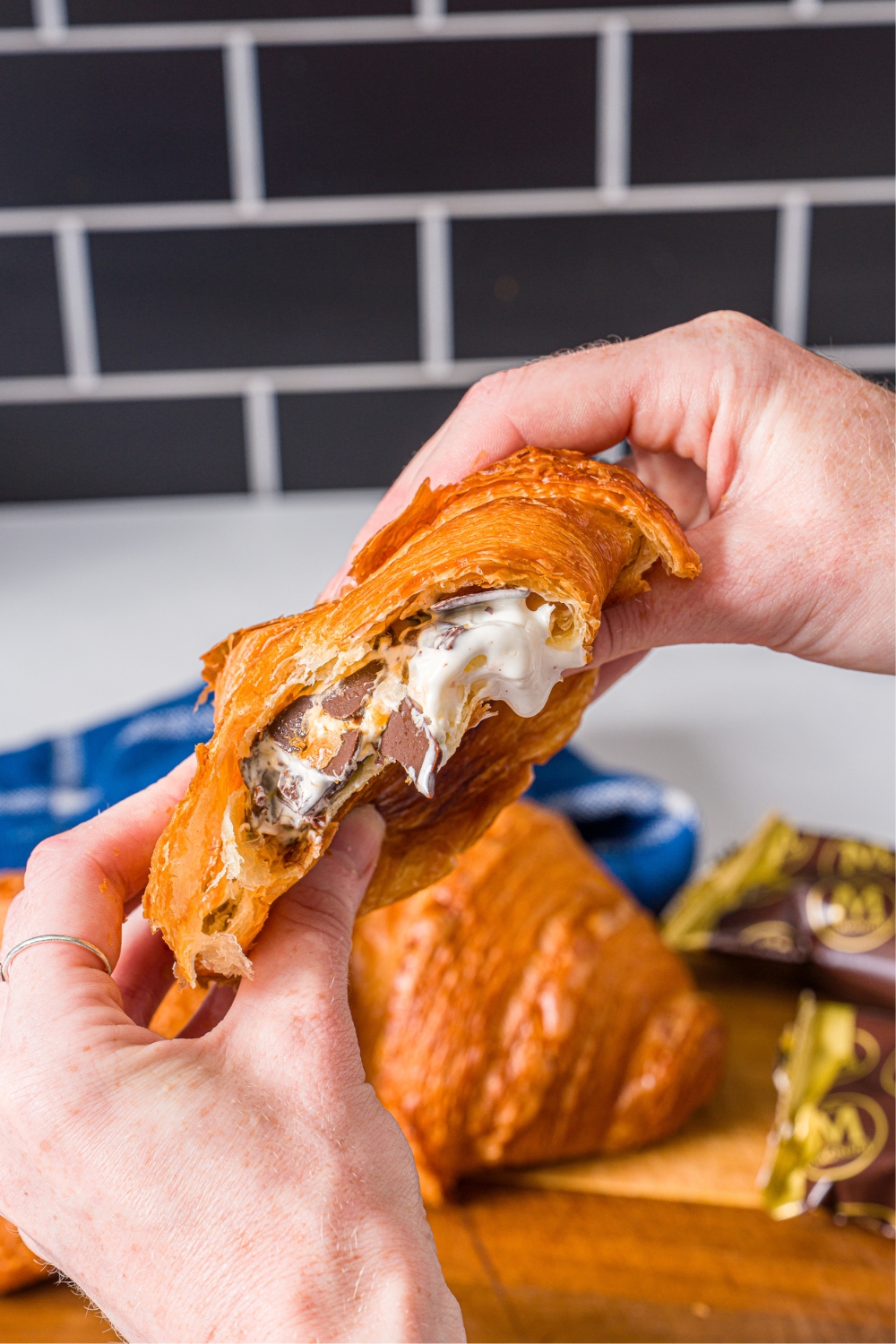 Two hands holding and smushing an ice cream bar in a croissant.
