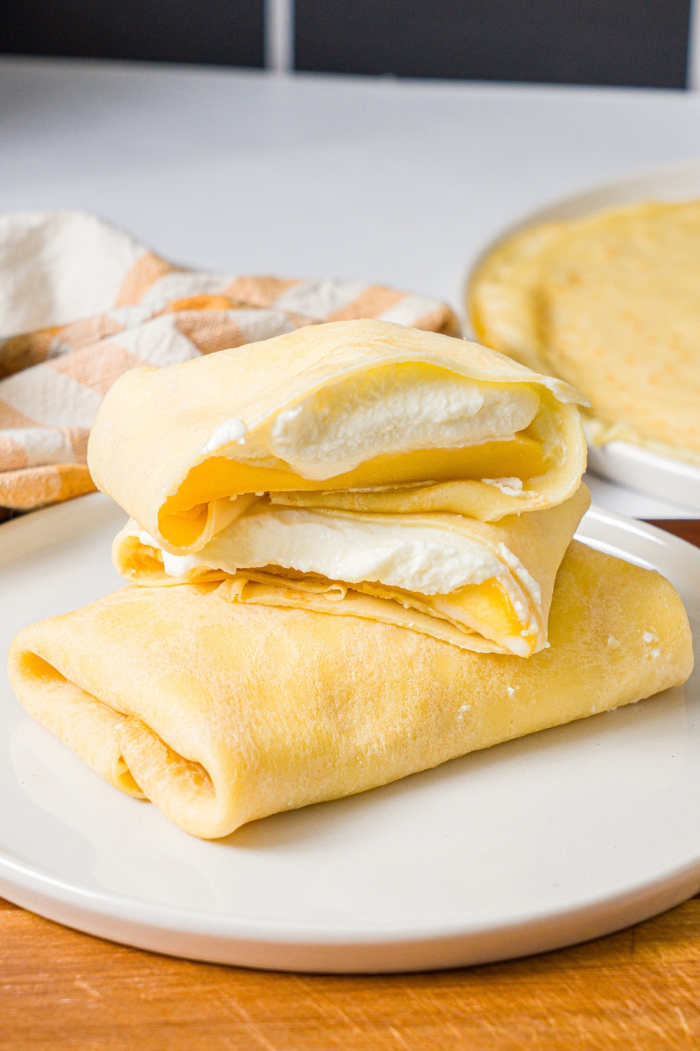 Two mango pancakes on top of one another. The bottom one is a whole mango pancake, and on top of that is the other mango pancake cut in half with the two halves on top of one another.