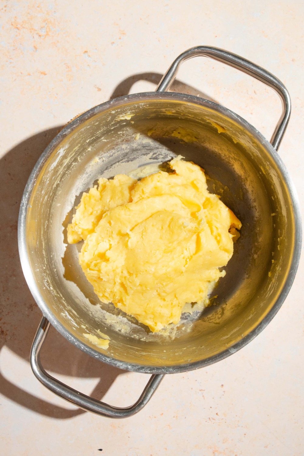 Mini churro dough in a stainless steel pot.