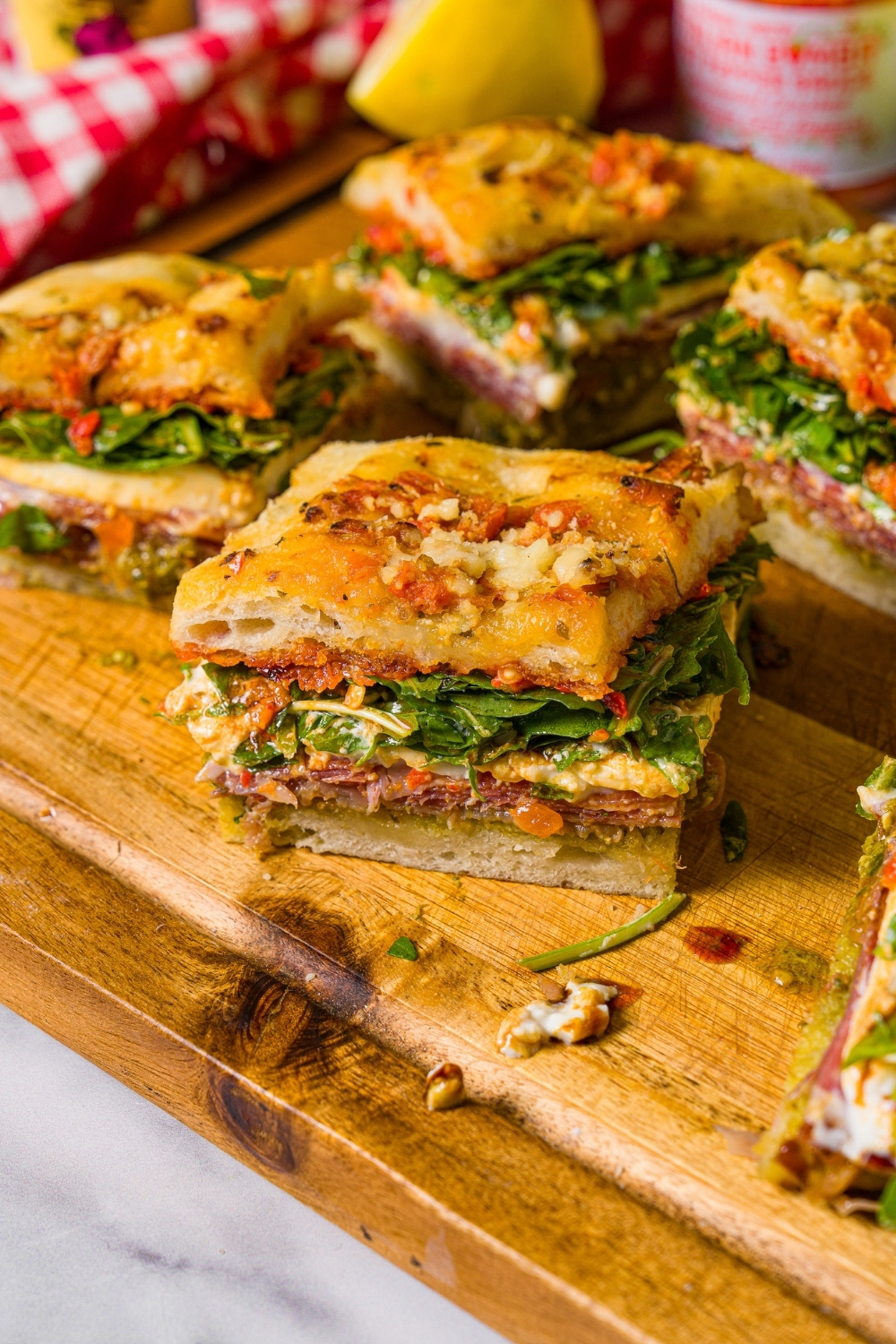 A square of Trader Joe's focaccia sandwich on a wooden cutting board with more squares of the sandwich behind it.