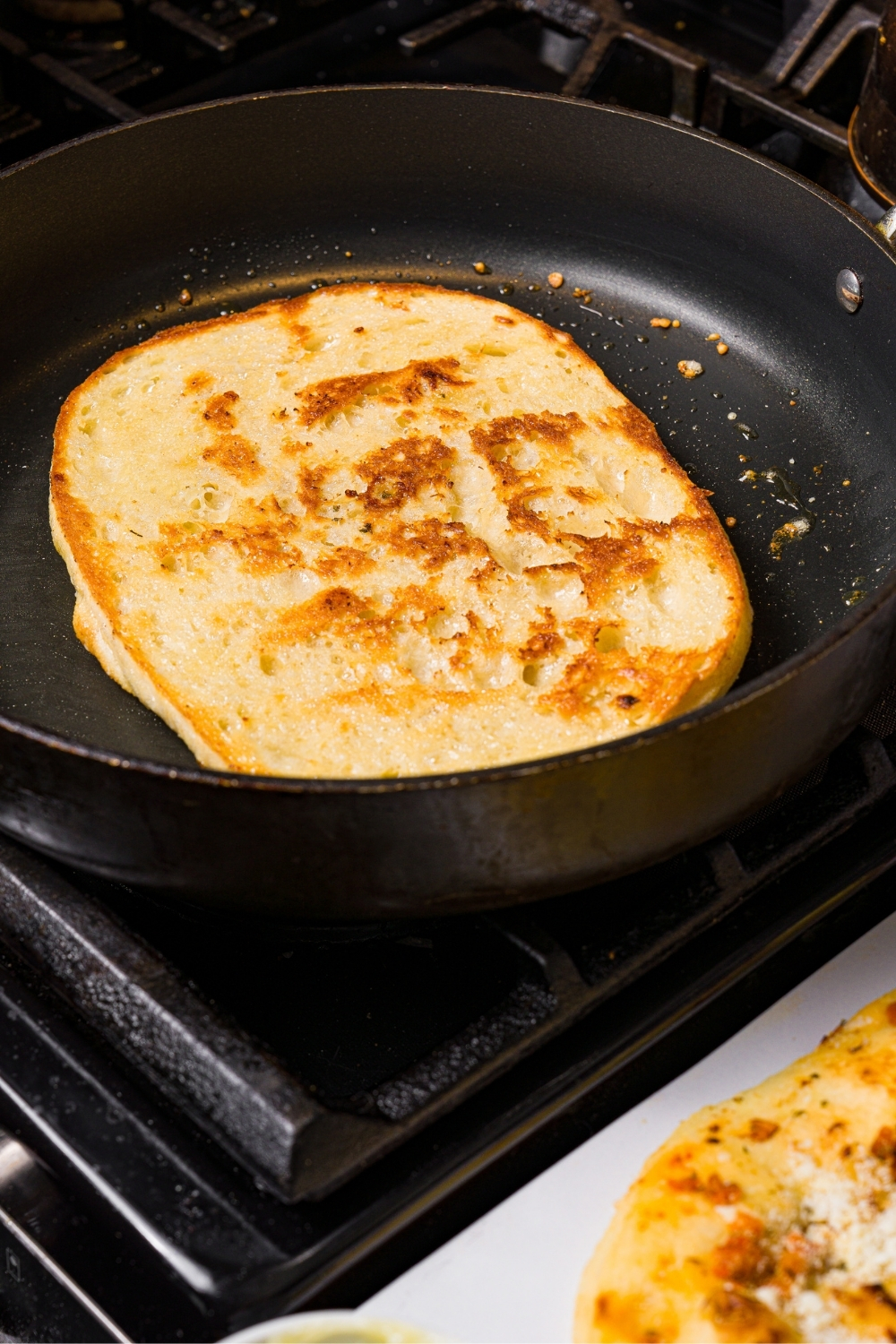 A slice of focaccia toasting a skillet.