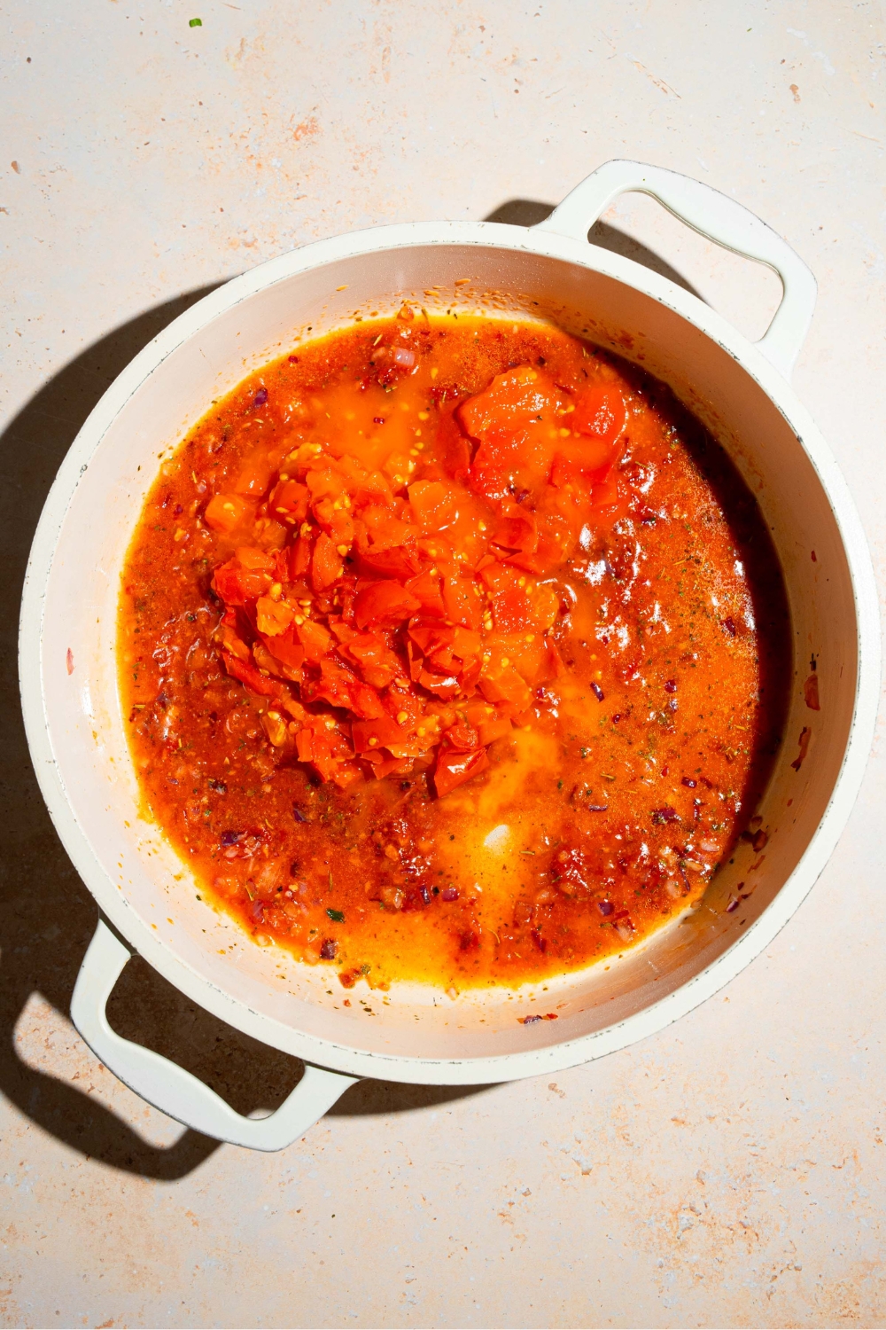 A tomato sauce cooking in a white pot.