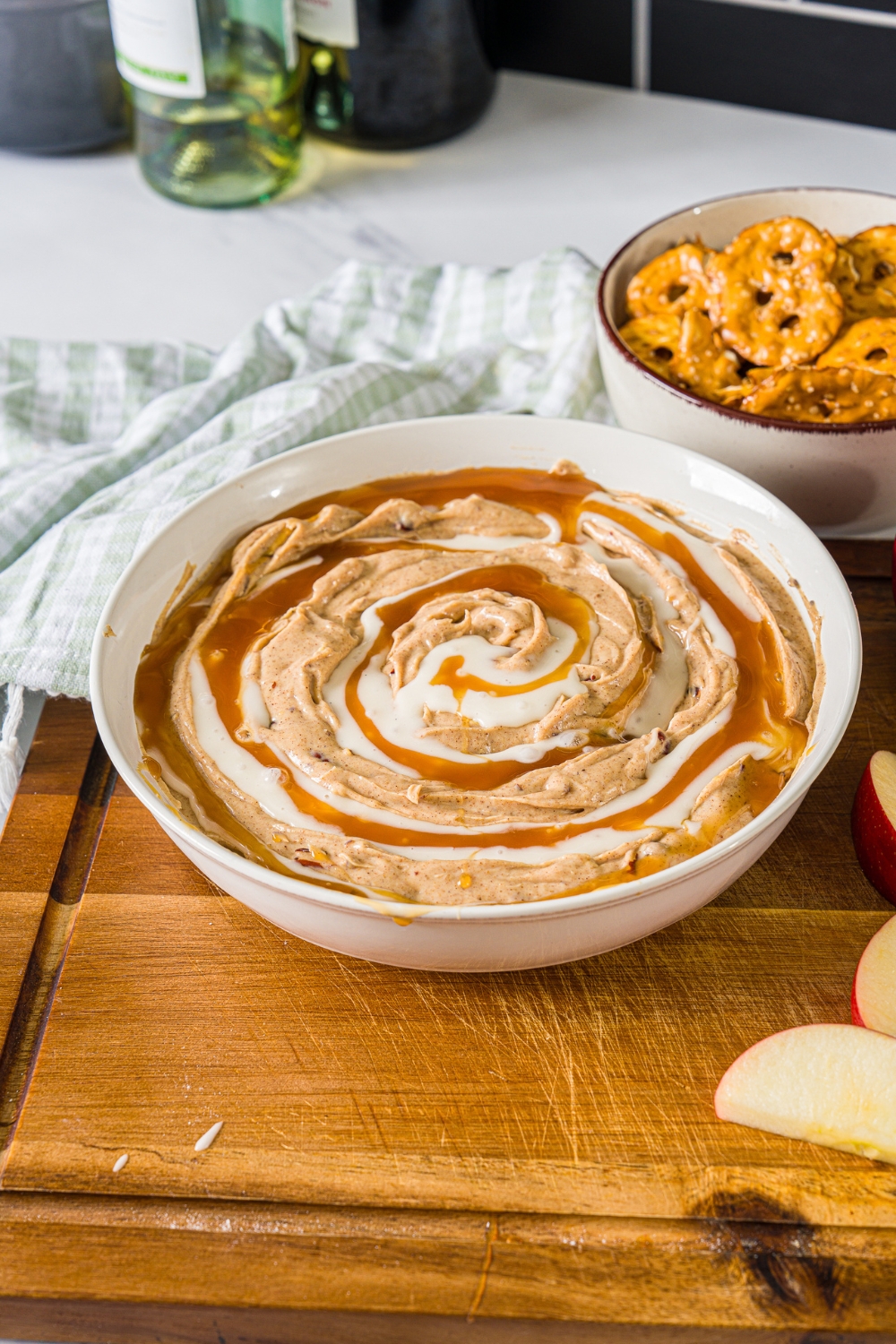 Cinnamon roll dip with icing and caramel sauce in a white bowl.