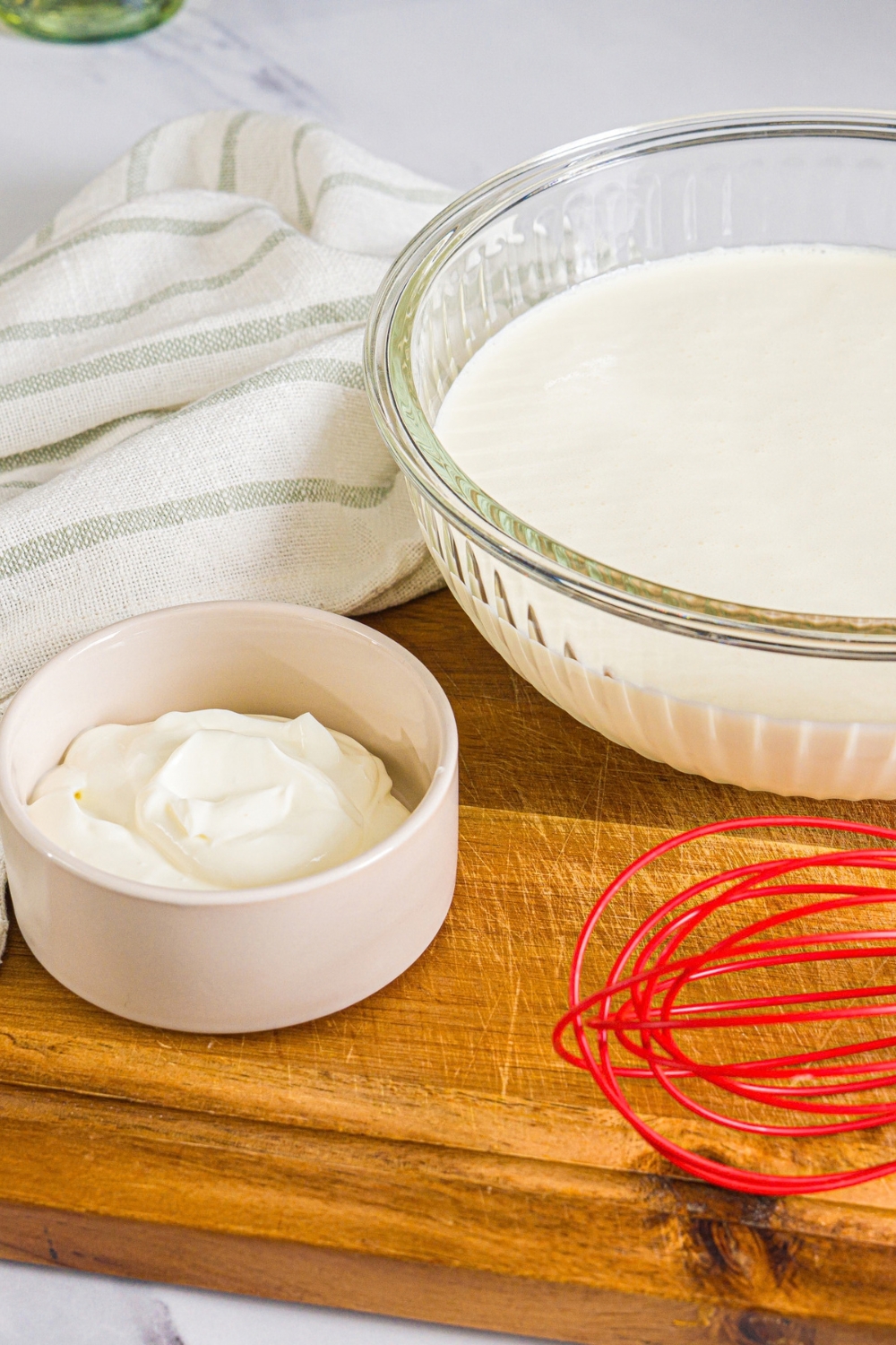 A wooden board with ingredients to make cultured butter including heavy cream and live yogurt culture.