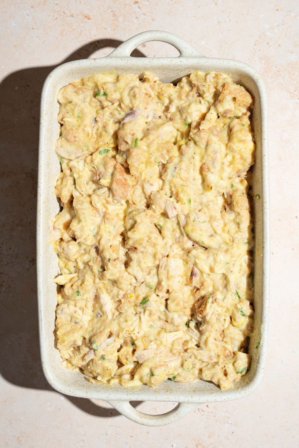 A baking dish with a chicken and stuffing casserole mixture. The dish is on a tan counter.