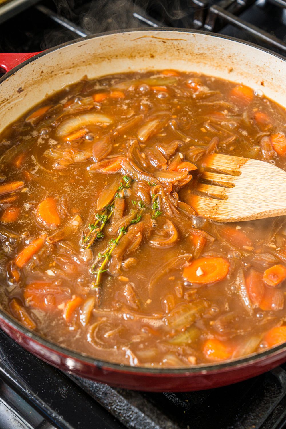 A dutch oven with french onion and broth mixture. The dutch oven is cooking on the stove.