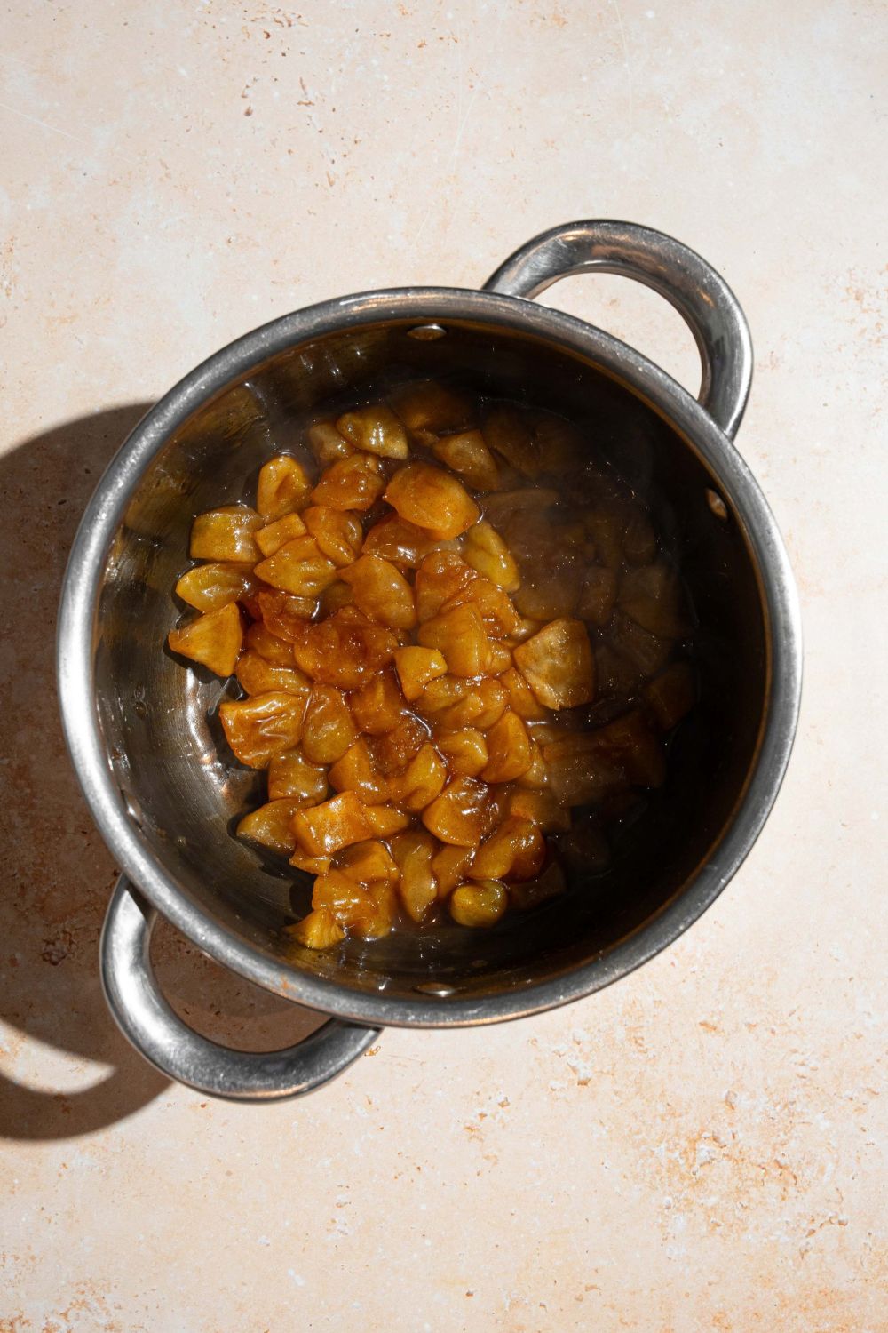 A pot with cooked apple pie filling. The pot is on a tan counter.