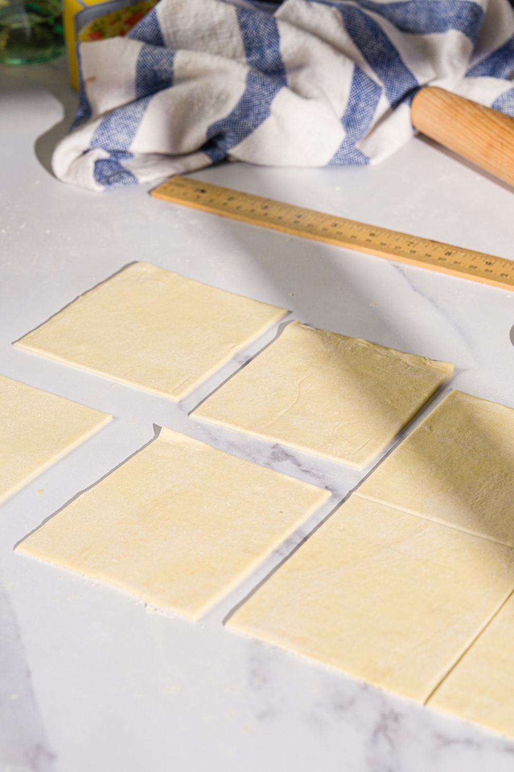 A marble counter with puff pastry sheets sliced into squares.