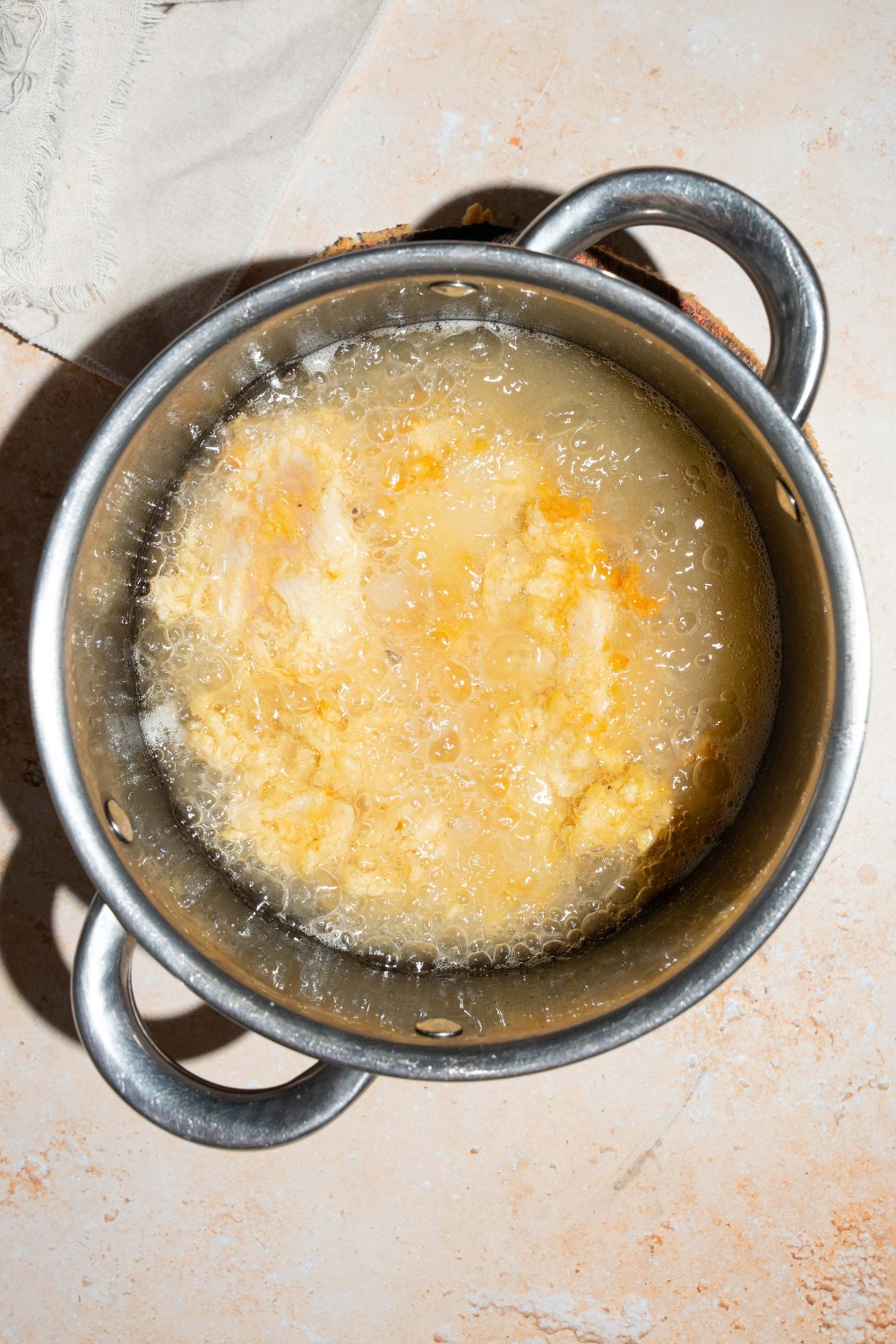 A large pot with copycat Chick-Fil-A tenders frying in oil. The pot is on a tan counter.