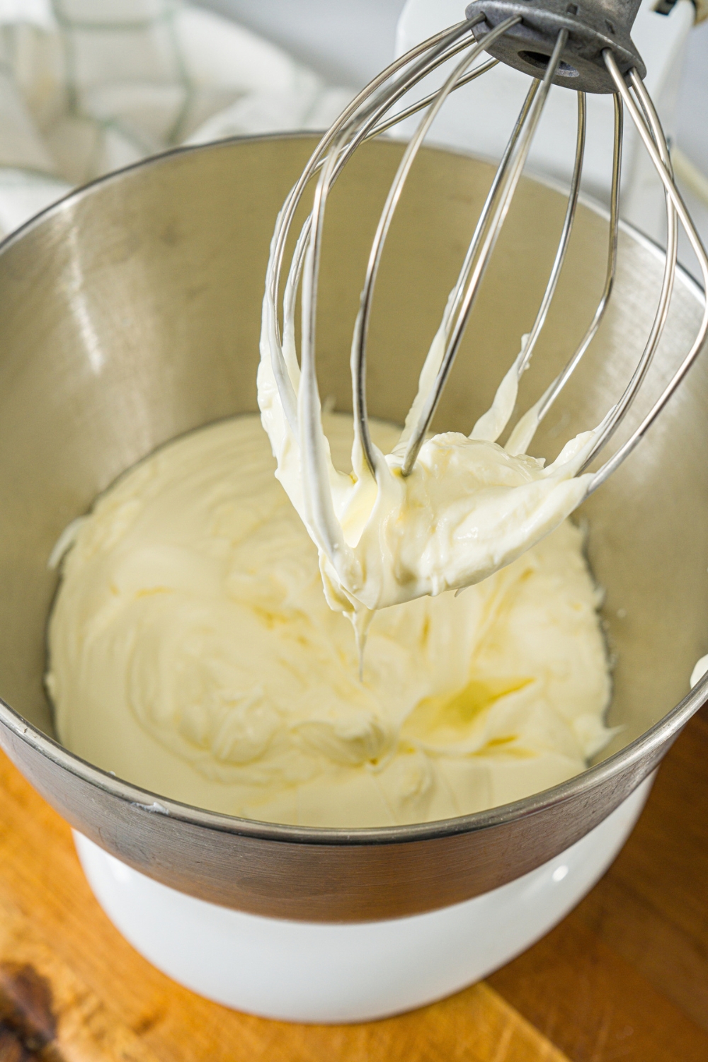 A yogurt and cream mixture in a stand mixer bowl. A stand mixer whisk has been dipped in the mixture.