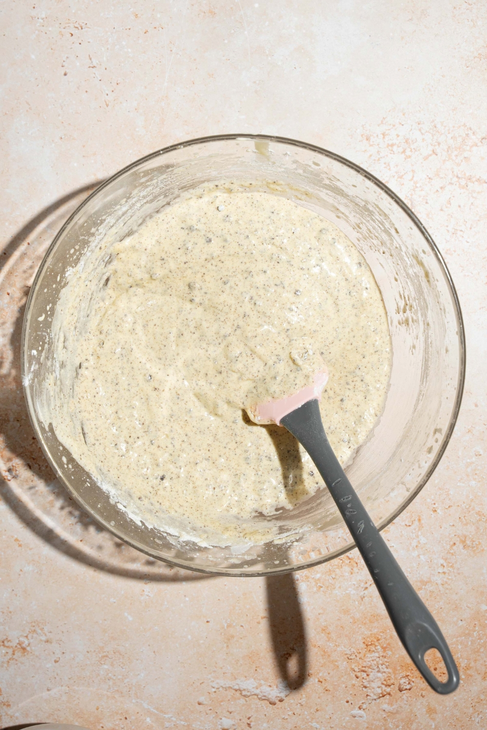 A large bowl with Oreo tres leches cake batter with a spatula in the batter. The bowl is on a tan counter.